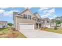 Angle view of a two-story home with a two-car garage, tan siding, stone accents, driveway, and landscaped yard at 7006 Shooting Star Way, Myrtle Beach, SC 29579