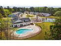 Community pool and clubhouse surrounded by lush landscaping and trees at 1149 Windy Grove Ln Sw # 15, Ocean Isle Beach, NC 28469