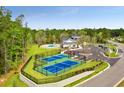 Aerial view of community tennis courts, pool, clubhouse, and parking area at 1149 Windy Grove Ln Sw # 15, Ocean Isle Beach, NC 28469