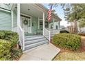 Inviting front porch with grey stairs, white railings, and an American flag waving at 4413 Bed Straw Ct., Murrells Inlet, SC 29576