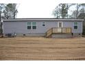 The side of the house is covered in gray siding, highlighted by an exterior deck with natural wood stairs at 5810 Hwy 9, Nichols, SC 29581