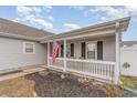 Inviting covered front porch with white railing, American flag, and cozy seating, perfect for relaxing outdoors at 9545 Sullivan Dr., Murrells Inlet, SC 29576