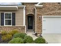 Close-up of the front entrance, showcasing the stone facade, black door, and landscaping at 1442 Chanson Ct., Little River, SC 29566