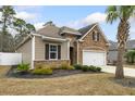 A charming home featuring a stone facade, manicured lawn with mulch beds, and complemented by a swaying palm tree at 1442 Chanson Ct., Little River, SC 29566