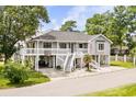 Charming gray beach house on stilts with white railings and a welcoming staircase entrance at 202 Old Harbour Ct., Little River, SC 29566