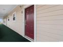 Hallway view of condo unit exterior with red door and carpeted walkway at 5751 Oyster Catcher Dr. # 633, North Myrtle Beach, SC 29582