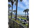 Relaxing outdoor lounge area with beach access, featuring lawn chairs, palm trees, and ocean views at 201 77Th Ave. N # 420, Myrtle Beach, SC 29577