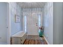 Bright entryway featuring a glass-paneled front door, complemented by a stylish wood floor and soft blue walls at 920 Leather Leaf Ln., Longs, SC 29568