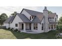 Rear view of home highlighting covered porch, stone chimney, manicured lawn, and architectural details at 9413 Park St., Myrtle Beach, SC 29572