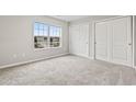 Bright bedroom featuring neutral walls, carpet floors, large window, and double door closet at 125 South Shore Blvd. # 201, Longs, SC 29568