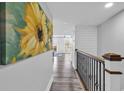 Bright hallway features hardwood floors, fresh white walls, eye-catching sunflower artwork, and ornate wrought iron railing at 423 Parker Dr. # 306, Pawleys Island, SC 29585