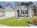 Exterior shot of a well-maintained home with green lawn, stone details, and a two-car garage at 616 Choctaw Dr., Conway, SC 29526