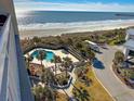 Aerial balcony view of the outdoor pool, beach, and ocean at this charming beachside resort at 9820 Queensway Blvd. # 706, Myrtle Beach, SC 29572