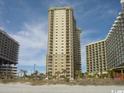 A luxury high-rise condo building is set on a sandy beach with blue sky background at 9994 Beach Club Dr. # 2408, Myrtle Beach, SC 29572