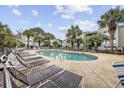 Inviting community pool surrounded by lounge chairs and palm trees for relaxation at 100 Spanish Oak Ct. # H, Surfside Beach, SC 29575