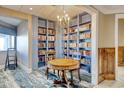 Well-stocked library featuring beautiful custom shelving, a round table, and decorative chandelier at 9650 Shore Dr. # 503, Myrtle Beach, SC 29572