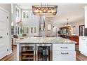 A modern kitchen island featuring a wine cooler, marble countertop, and a custom light fixture at 11455 W Highway 19, Loris, SC 29569