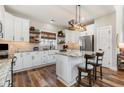 A bright kitchen with white cabinets, an island with seating, stainless steel appliances, and brick backsplash at 11455 W Highway 19, Loris, SC 29569