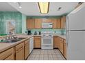 Bright kitchen featuring white appliances, wooden cabinetry, and tile flooring at 1221 Tidewater Dr. # 321, North Myrtle Beach, SC 29582