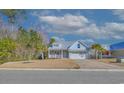 Charming light blue home with metal roof, inviting front porch, two-car garage, and a neatly maintained lawn at 377 Waties Dr., Murrells Inlet, SC 29576