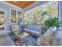 Inviting screened porch with comfortable seating, stylish décor, wooden ceiling, and views of the surrounding trees at 377 Waties Dr., Murrells Inlet, SC 29576