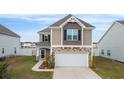 Front view of two-story home featuring stone accents, a two-car garage, and a well-maintained lawn at 5519 Redleaf Rose Dr., Myrtle Beach, SC 29579