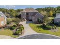 A luxurious red brick home is surrounded by lush landscaping and mature trees on a sprawling lot at 6575 Sw Longwater Ct., Ocean Isle Beach, NC 28469