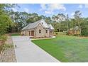 Side view of a charming brick home with a long driveway leading to an attached two-car garage at 1328 Foxtail Dr., Longs, SC 29568