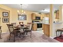 A dining area next to the kitchen featuring oak cabinets, a chandelier, and modern appliances at 2276 Essex Dr. # H, Surfside Beach, SC 29575