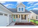 Light gray home featuring a striking turquoise front door, white garage door, and covered porch at 507 Rose Fountain Dr., Myrtle Beach, SC 29579