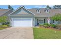 Inviting home with a white garage door, landscaped yard, and charming details. American flag displayed for added curb appeal at 662 Sunnyside Dr. # 101, Murrells Inlet, SC 29576