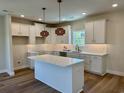 Bright kitchen features white cabinets, a center island with a marble countertop, and stylish pendant lighting at 713 9Th Ave. S, North Myrtle Beach, SC 29582