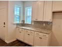Elegant kitchen featuring stylish backsplash, granite counters, and white cabinets with ample storage at 8643 Farrier Dr., Myrtle Beach, SC 29588