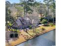 Waterfront home featuring mature trees, beautiful landscaping, and brick exterior at 1616 Hawthorn Dr., Pawleys Island, SC 29585