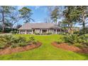 Beautiful one-story brick home with a lush green lawn, mature trees, and attractive landscaping at 1616 Hawthorn Dr., Pawleys Island, SC 29585