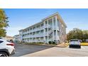 Three-story condo building with pale blue siding, white stairs and railings, and stone accents on a sunny day at 4655 Wild Iris Dr. # 101, Myrtle Beach, SC 29577