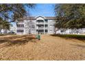 Condo building with stone facade, white railings, and lots of windows under a bright blue sky, viewed through trees at 4655 Wild Iris Dr. # 101, Myrtle Beach, SC 29577