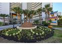 Resort entrance with palm trees and a flower garden, plus a resort sign at 5200 N Ocean Blvd. # 155, Myrtle Beach, SC 29577