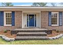 A welcoming blue front door with a wreath sits behind brick steps and manicured landscaping at 83 Pond St., Georgetown, SC 29440