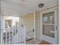 Covered porch entrance to a tan condo featuring a white door and railings leading to the stairs at 135 Butkus Dr. # 5, Myrtle Beach, SC 29588