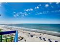 Expansive ocean view from a high-rise condo overlooking a beach full of sunbathers and blue umbrellas at 2500 N Ocean Blvd. # 705, North Myrtle Beach, SC 29582