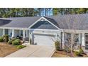 Aerial view of a charming single story home featuring a two-car garage, tidy landscaping and a quaint covered porch at 309 Lake Mist Ct. # 309, Longs, SC 29568