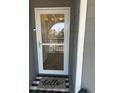 View of front door with storm door and welcome mat on gray porch at 4519 N Plantation Harbour Dr. # X - 19, Little River, SC 29566