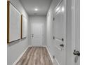 Hallway with wood-look floors and white doors showcasing modern artwork on the gray walls at 971 Laconic Dr., Myrtle Beach, SC 29588