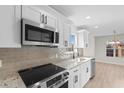Stylish kitchen boasts granite countertops, stainless steel microwave, electric range, and white cabinetry at 2483 Morlynn Dr., Myrtle Beach, SC 29577