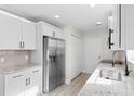 Updated kitchen showcasing stainless steel refrigerator, granite counters, white cabinets, and tile backsplash at 2483 Morlynn Dr., Myrtle Beach, SC 29577