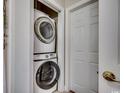 Modern stacked washer and dryer units in a closet with a white door ajar, offering convenience at 123 Avian Dr. # 102, Pawleys Island, SC 29585