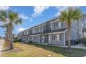 A line of two story townhomes shows a well-maintained facade with blue/gray siding and palm trees at 1881 Colony Dr. # 8-S, Surfside Beach, SC 29575