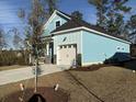 Side view of a two-story light blue house showing the garage and manicured lawn at 3121 Tiger Tail Rd., Conway, SC 29526