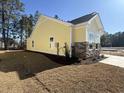 Side view of a yellow home with a stone foundation, showing a well-maintained lawn and landscaping at 3135 Tiger Tail Rd., Conway, SC 29526